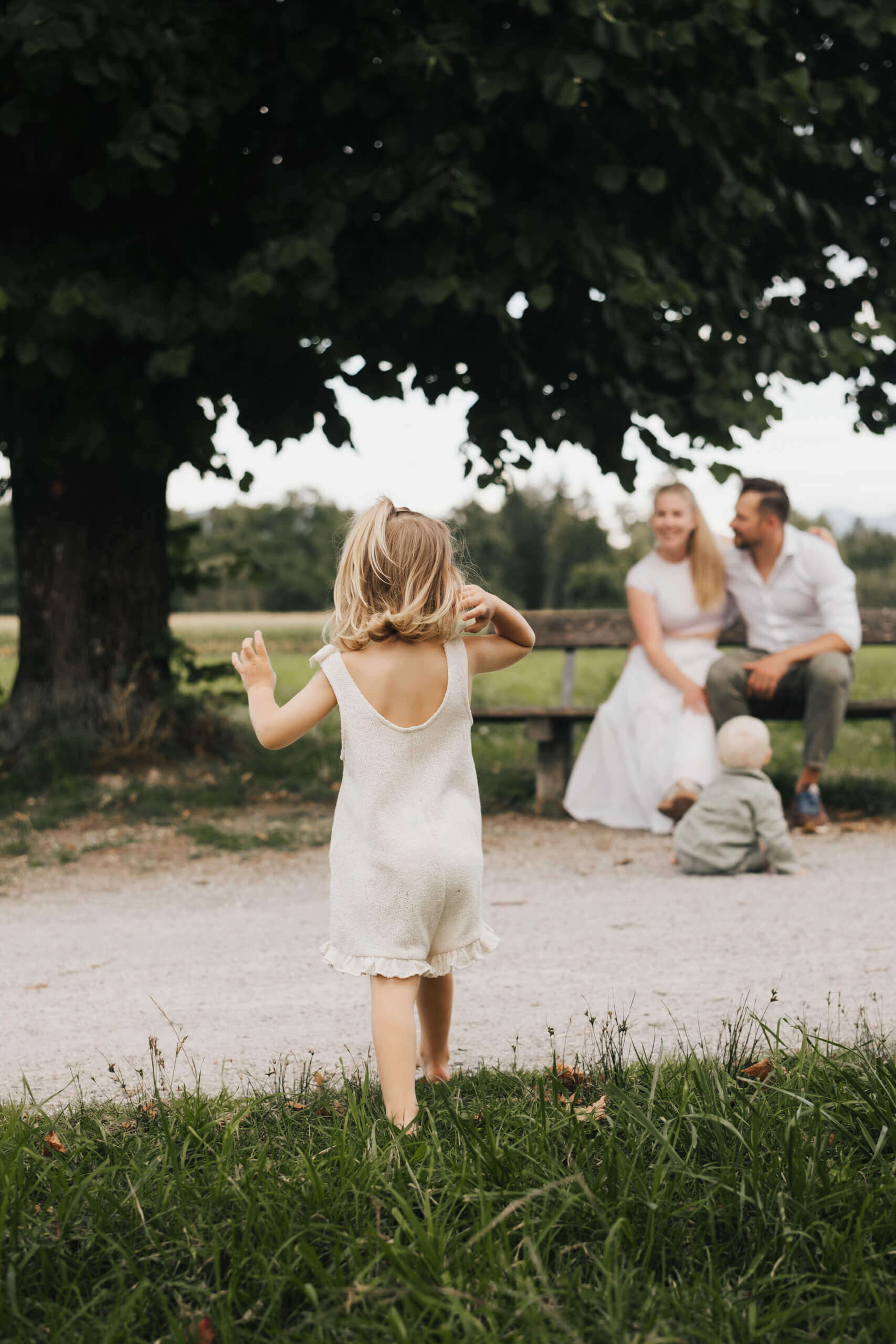 Familienfotografie in Salzburg: Kleines Mädchen läuft auf Eltern und Baby zu
