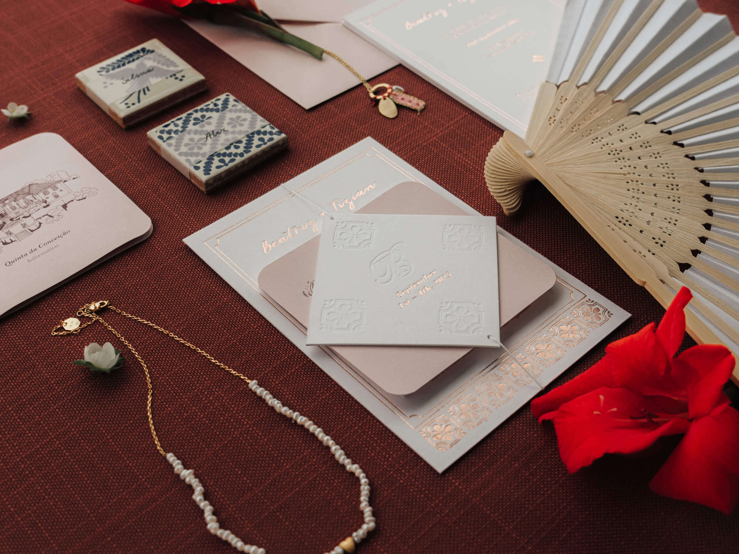 Hochzeitspapeterie mit Gravur und Schmuck, im Hintergrund Fächer und Blumen