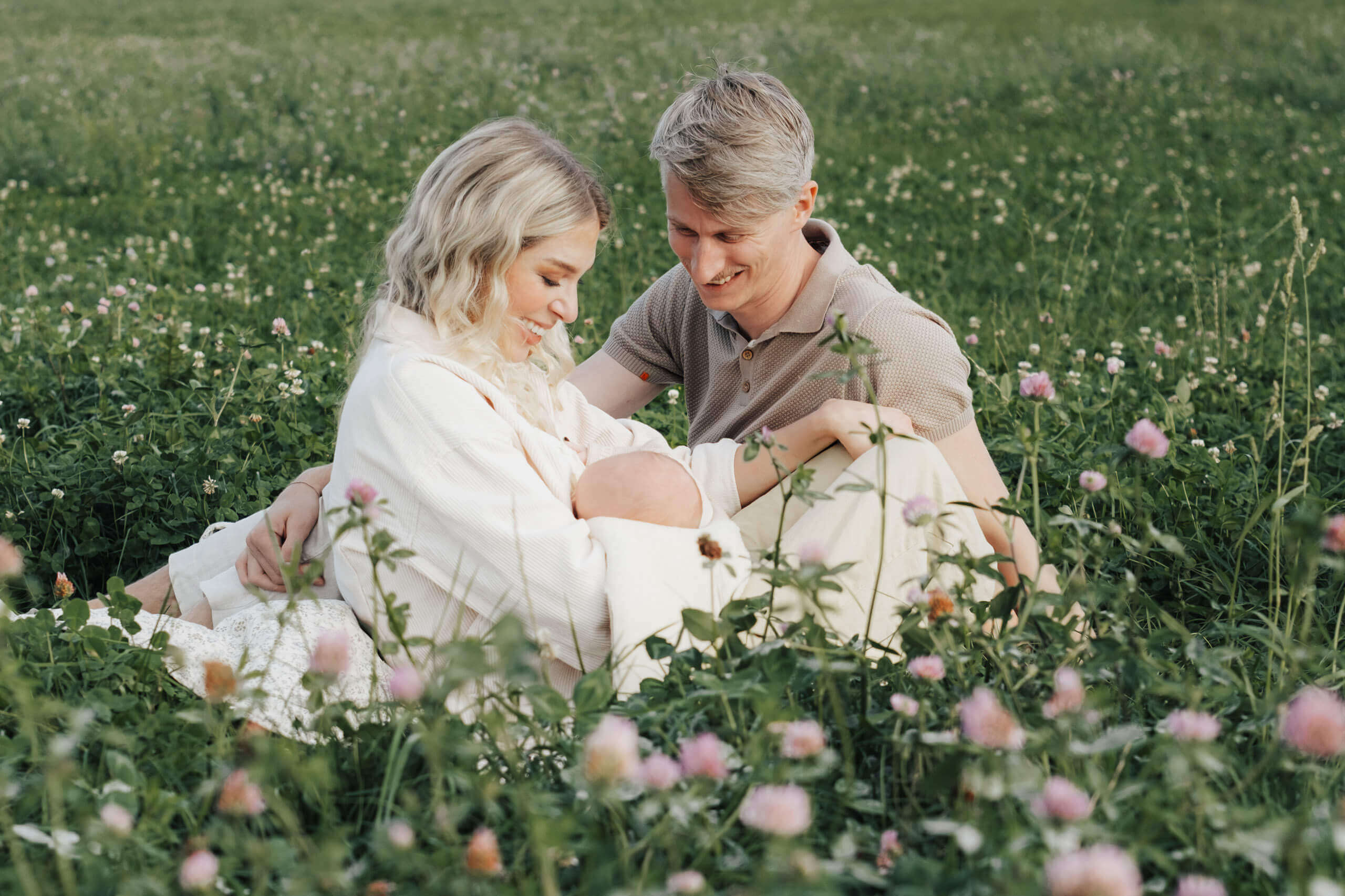 Junge Familie mit Neugeborenem im Gras, Familienfotografie in Salzburg